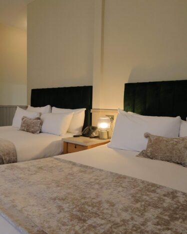 Elegant hotel room with two plush double beds, soft lighting, and modern decor ensuring a restful stay.