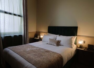 Cosy hotel room with plush double bed, soft lighting, elegant decor, and bedside table; perfect for a relaxing stay.
